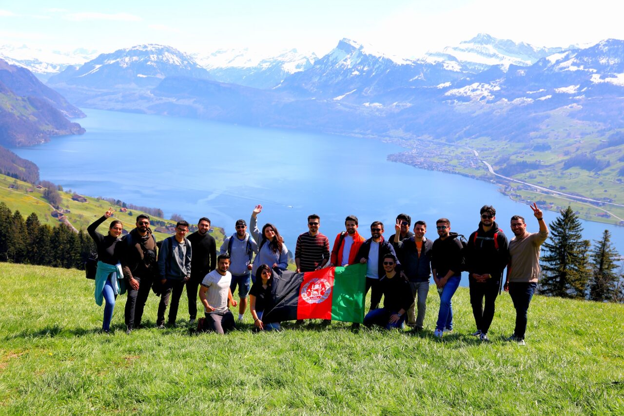 Group of students in front of a lake, holding the afghan flag