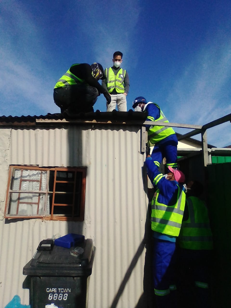 Four men with yellow vests climbing on a roof