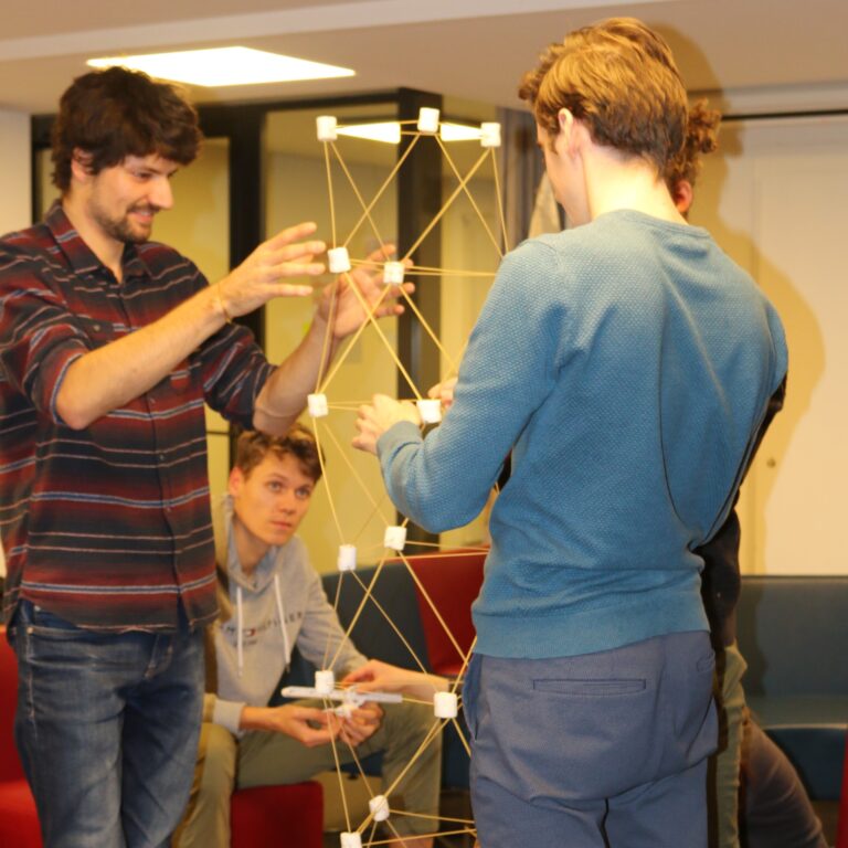Two men building a tower made of thin sticks